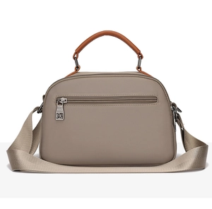 Close-up of khaki waterproof oxford fabric bag with brown leather handle and metal buckle