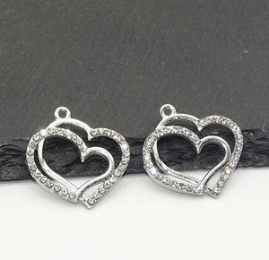 Detailed view of two silver hollow heart pendants with sparkling inset rhinestones