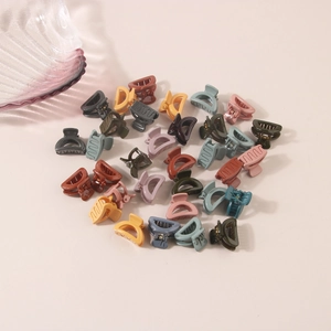 Close-up of colorful mini flower hair clips scattered on a soft pink surface