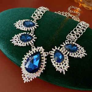 Detailed view of French vintage necklace with blue teardrop stones on green velvet