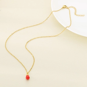 Dettaglio di una collana creativa in acciaio inossidabile dorato con ciondolo rosso