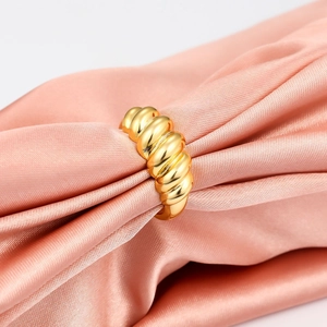 Polished gold croissant dome ring on pink silk fabric, elegant twisted rope jewelry style