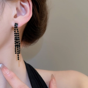 Gros plan de boucles d'oreilles à pompons en strass noirs portées par un mannequin