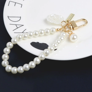 Porte-clés élégant en perles avec pendentif coquillage et fermoir doré sur assiette