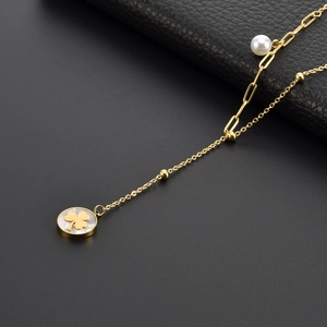 Golden double-layer necklace with clover pendant and pearl on dark background