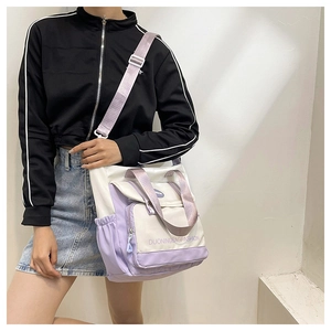 Detail of canvas tote bag showing side drawstring pocket and front zipper compartment