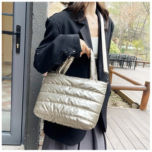 Detail of champagne silver quilted puffer tote bag with adjustable beige strap on model