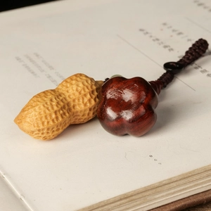 Artistic close-up of hand-carved rosewood peanut and flower charm on vintage book pages