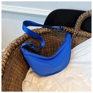 Detail of bright blue nylon crescent bag inside a textured woven basket setup