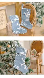 Detail einer hellblauen Plüsch-Weihnachtssocke mit weißem Schneeflockenmuster am Baum