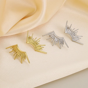 Detail view of gold and silver sunburst stud earrings on silk background texture