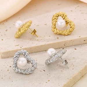 Detailed macro view of heart-shaped pearl earrings in both gold and silver finishes