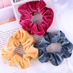 Close-up of soft velvet hair scrunchies in rose, yellow and blue grey on magazine