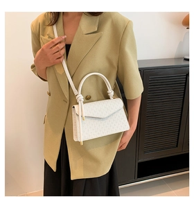 Close-up of white quilted crossbody bag featuring a knotted handle and geometric pattern