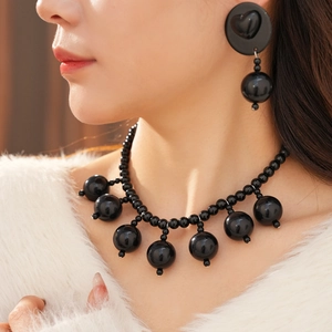 Close-up of black acrylic bead necklace and heart earrings set on a female model