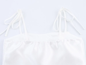 Detail of adjustable thin straps and square neckline on white satin two-piece set