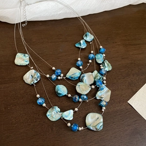 Detailed shot of multi-layer shell and crystal beaded necklace on a wooden background