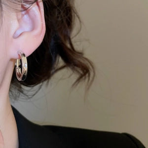 Side view of a minimalist silver geometric C-shape hoop earring worn by a model