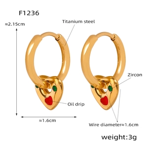 Detail view of gold titanium earrings featuring red enamel hearts and green zircon stones