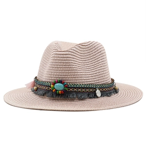 Close-up of pink woven straw sun hat with turquoise bead and bohemian fringe details