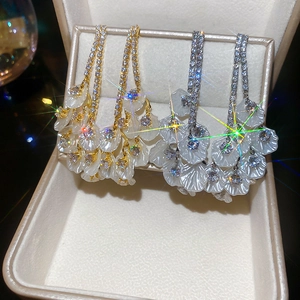 Détails de boucles d'oreilles pampilles dorées et argentées avec pétales dans un écrin chic
