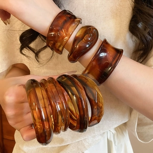 Detailed view of amber resin bangles showing tortoise shell patterns and glossy texture