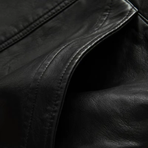 Macro shot of black PU leather texture with detailed double-stitched pocket seams