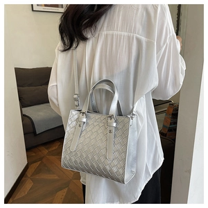 Detailed view of silver woven crossbody bag shown on model for realistic size and fit