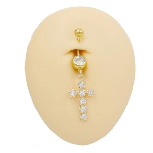 Détail d'un piercing de nombril doré avec pendentif croix et zircons sur un mannequin