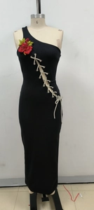 Détail d'une robe noire à une épaule avec fleur rouge et laçage latéral argenté