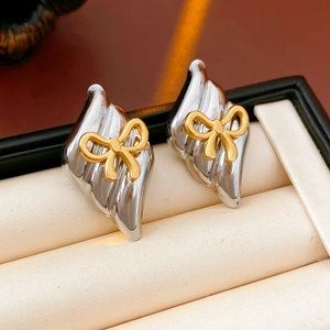 Macro shot of silver wave earrings with gold bow accents in a luxury jewelry box