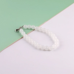 Macro detail of white glass pearl phone strap with a metallic lobster clasp closure