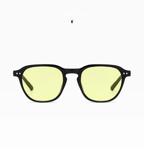 Detail of black frame sunglasses with yellow lenses and metal rivets on temples