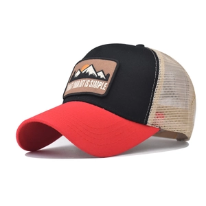 Dettaglio del cappello trucker con patch montagna e visiera rossa dal design aerato