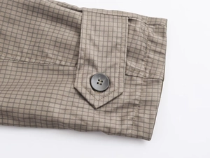 Close-up of khaki checkered fabric with a dark grey resin button and stitching detail