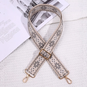 Detail of gray and white geometric woven bag strap with golden adjustable metal buckles