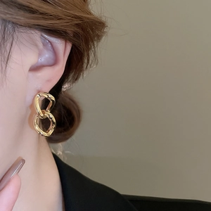Close-up of geometric gold chain link earrings worn on model for a minimalist chic style