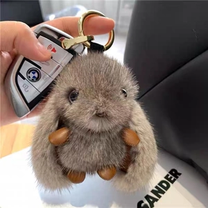 Close-up of a fluffy gray faux fur rabbit keychain with golden alloy ring and leather paws