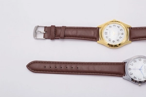 Detail of quartz watches with brown leather straps and numeric dials in gold and silver cases