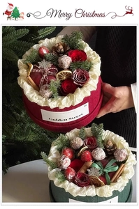 Close-up of Christmas flower gift box with roses, cinnamon sticks, and pine cones