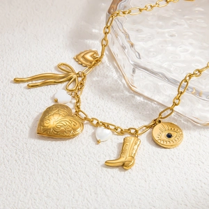 Détail d'un bracelet doré avec pendentif coeur, breloques papillon et bottes de cow-boy
