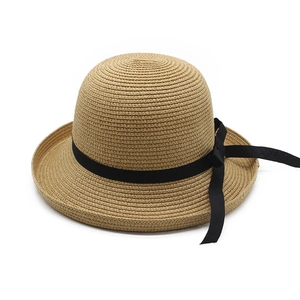 Detail of woven straw sun hat texture featuring a wide black ribbon bow decoration