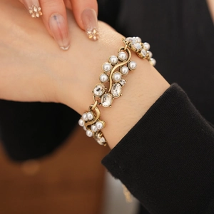 Close-up of vintage golden bracelet with white pearls and crystals on female wrist