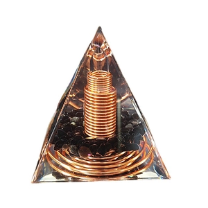 Handmade Orgone pyramid with crystal stones and spiral copper wire on white background