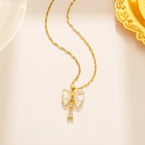 Detail of gold bow necklace with iridescent shell wings and sparkling clear gemstones