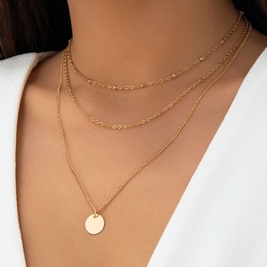 Detailed close-up of a three-layer gold necklace set featuring a round coin pendant charm