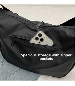 Macro shot of a black crossbody bag showing a zipper pocket holding a smartphone