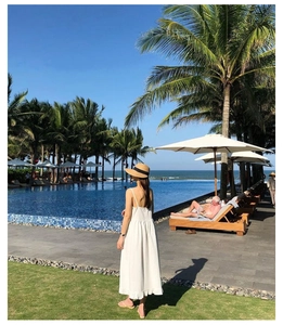 Rear view of a white maxi sun dress paired with a wide-brim straw hat by the pool