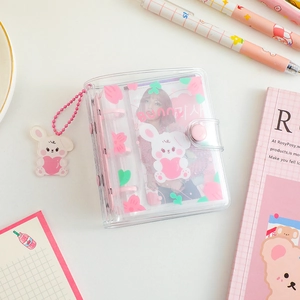 Detail of pink bunny mini PVC binder with cute pendant and snap closure on white desk