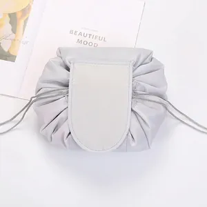 Flat lay of open silver drawstring makeup bag on white fabric with decorative card
